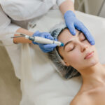 View from above rejuvenation of beautiful woman enjoying cosmetology procedures in beauty salon. Dermatology, hands in blue glows, healthcare, therapy, botox.