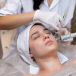 A young beautiful girl lies on the beautician's table and receives procedures with a professional apparatus for skin rejuvenation and moisturizing